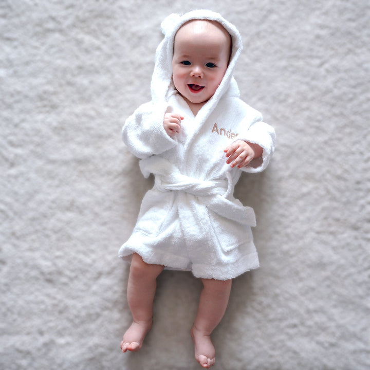 Baby in white bamboo robe with "Ander" customised in beige thread