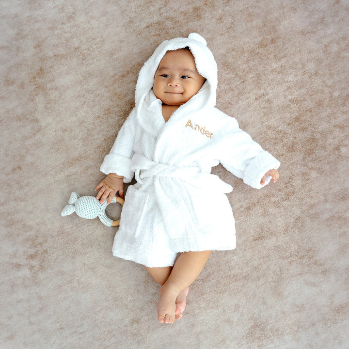 Baby in white bamboo robe with "Ander" customised in beige thread