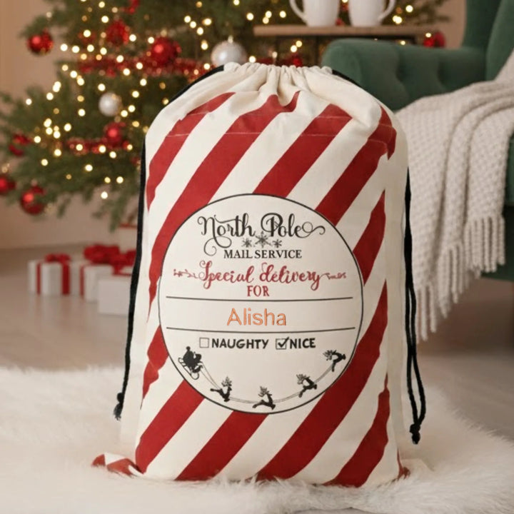 Red and white striped christmas bag with personalized label in a festive room.