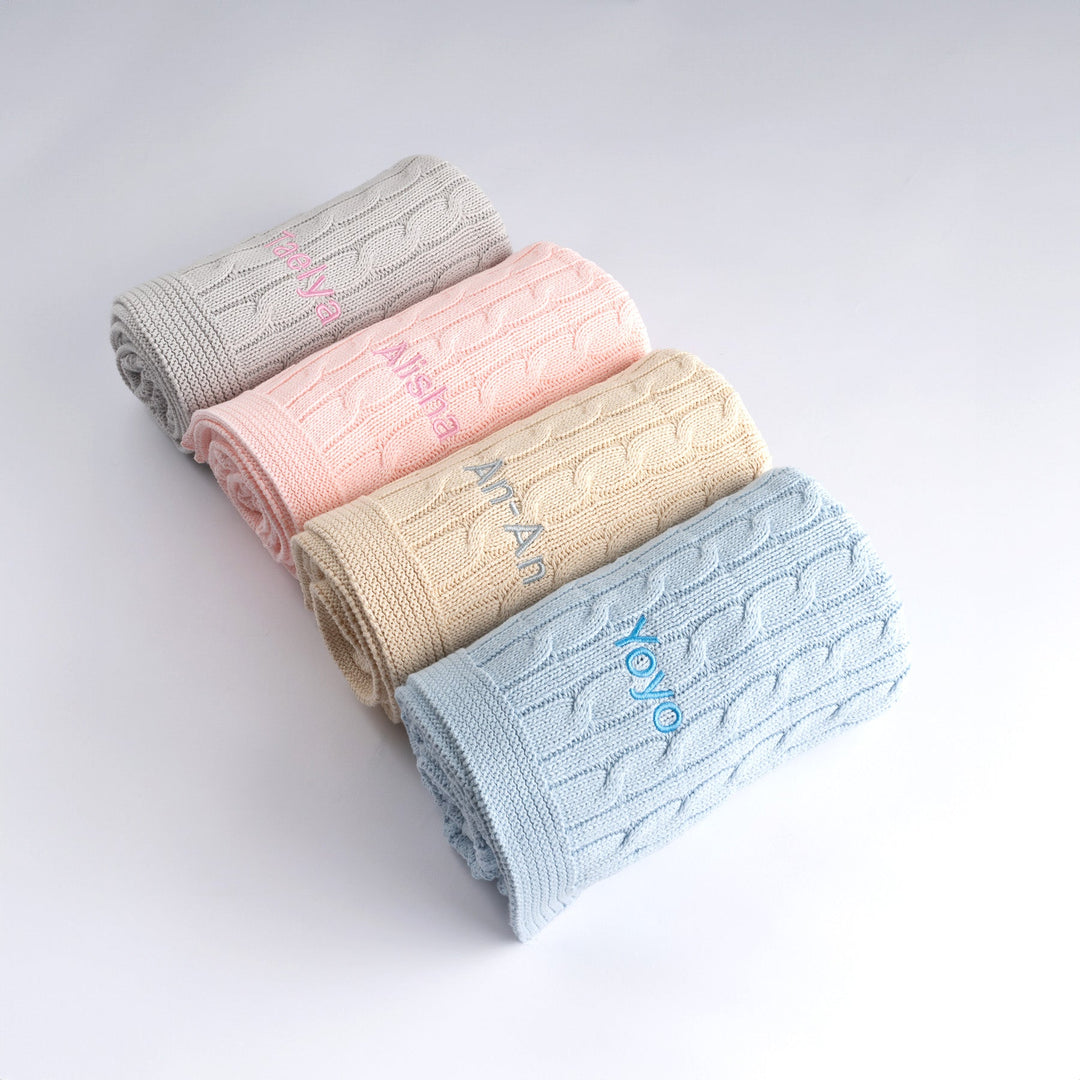 Elevate your baby's nursery with this luxurious cable knit blanket. Available in pink, grey, cream, and blue