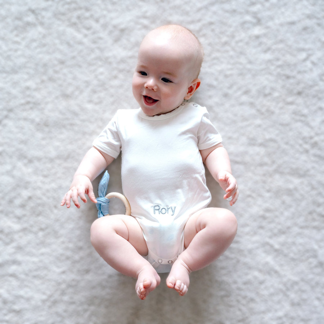 Baby in White Bamboo Babygrow playing with teether 