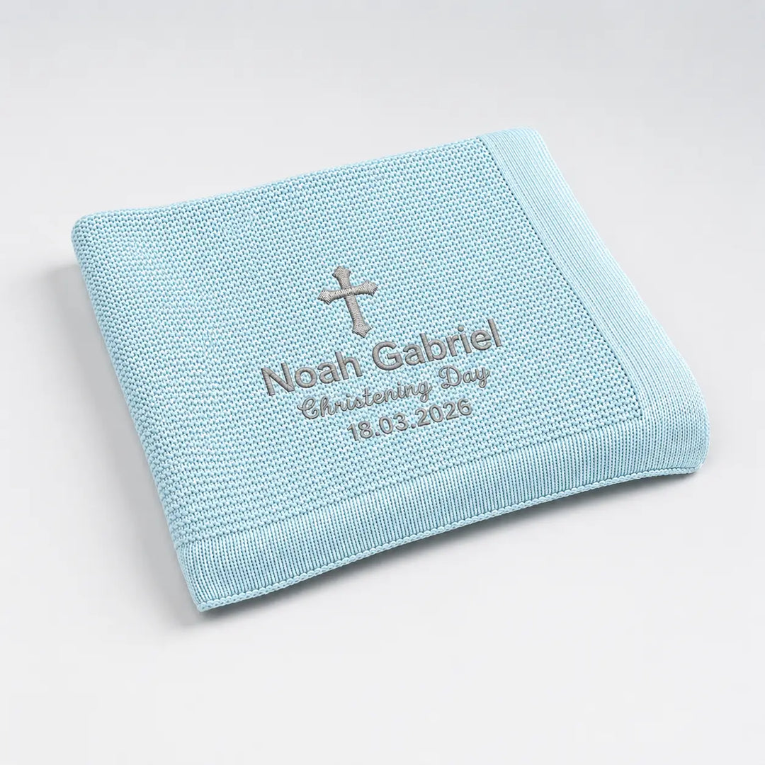 Light blue embroidered blanket with cross and text on a white background