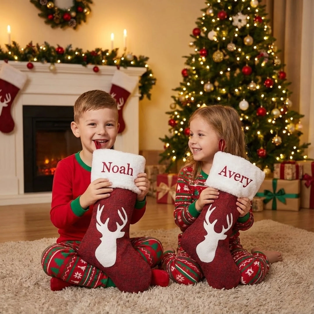 Two children holding personalized Christmas stockings in a festive living room.