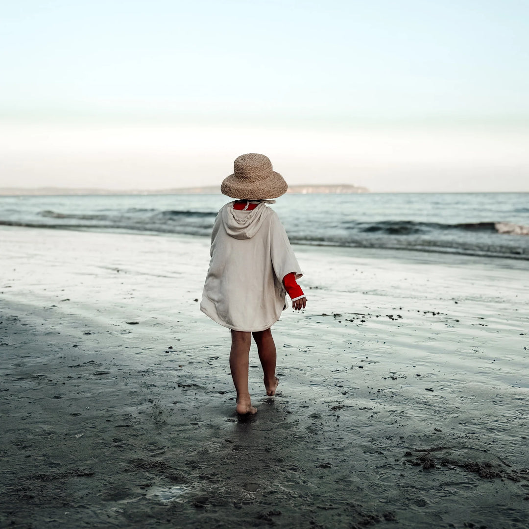 Back view of kid wearing Cosy Roots Organic UV Poncho - Sand