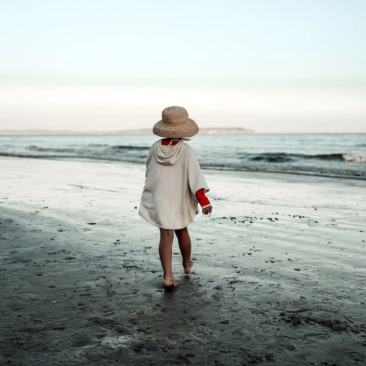 Back view of kid wearing Cosy Roots Organic UV Poncho - Sand
