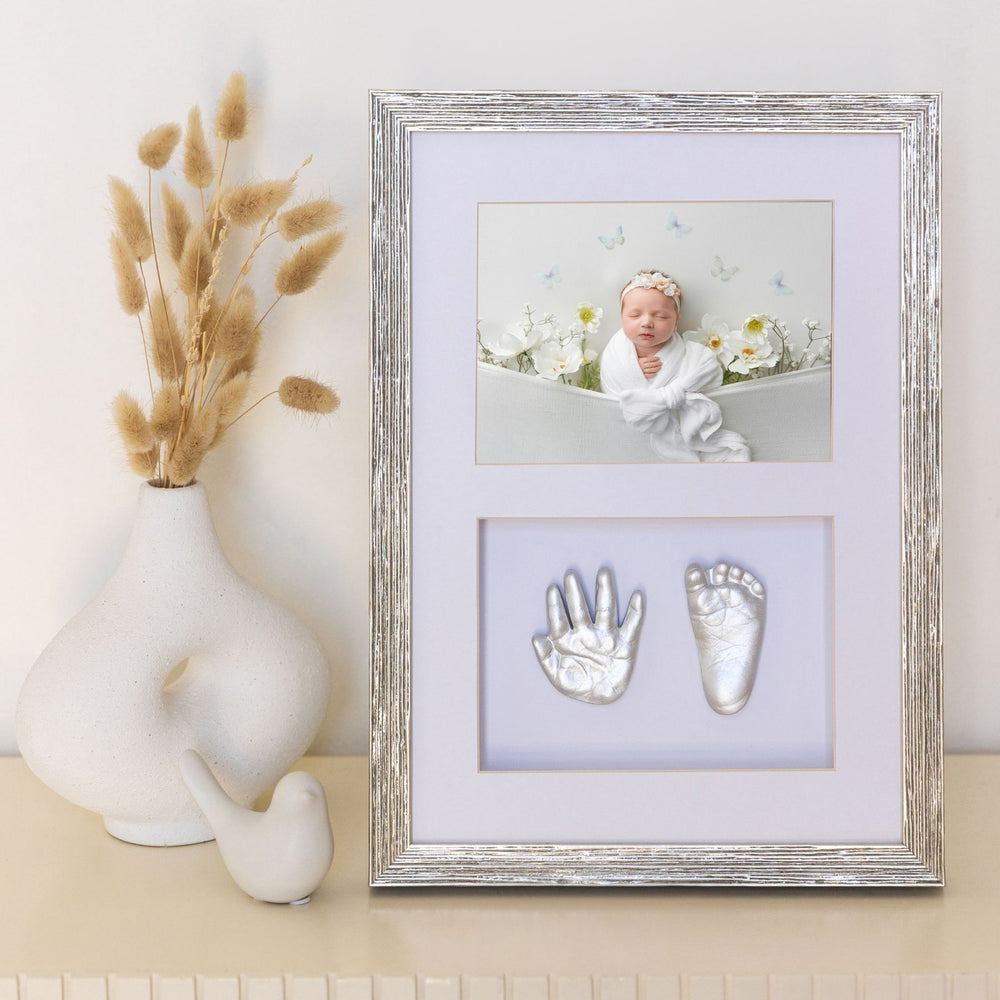 Framed baby photo with hand and footprints on a decorative shelf.