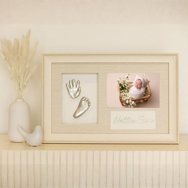Framed baby handprint and footprint with a photo of a baby in a crib on a decorative shelf.