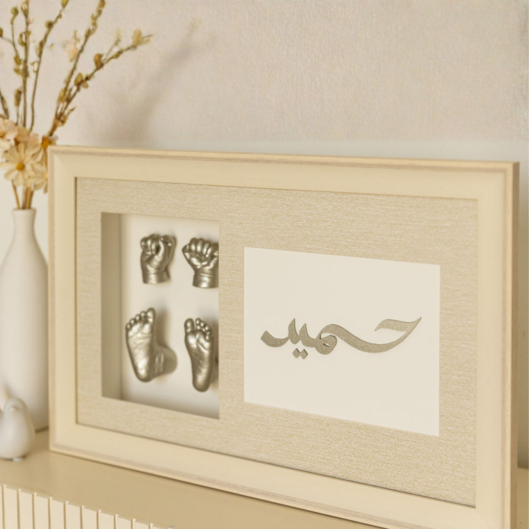 Framed metallic baby hand and footprints with Arabic text on a neutral background