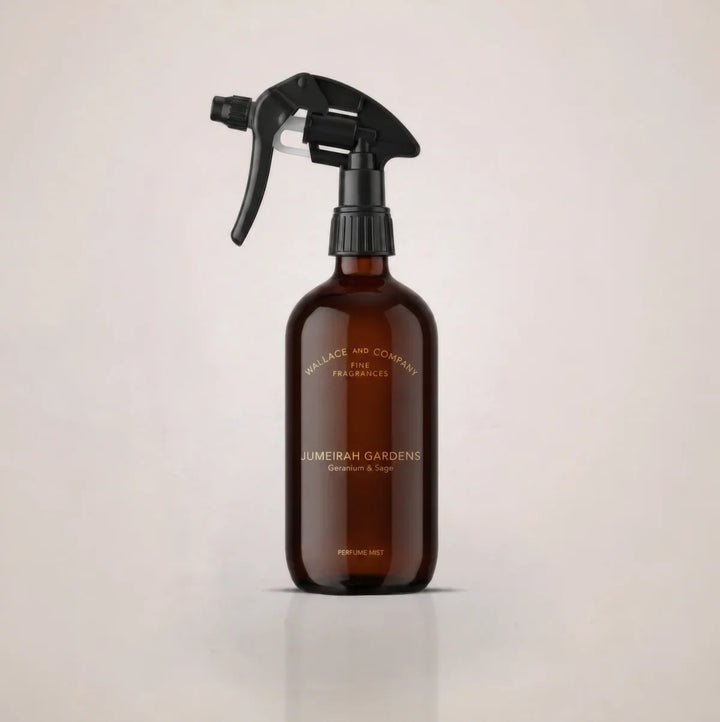 An amber glass spray bottle with a black trigger sprayer, featuring gold lettering that reads 'JUMEIRAH GARDEN' and 'Cleanse & Soothe' on a light beige background.