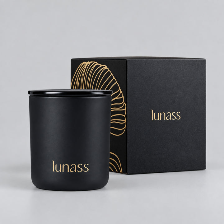 Black LUNASS luxury scented candle with matching black and gold presentation box on a light grey studio background.