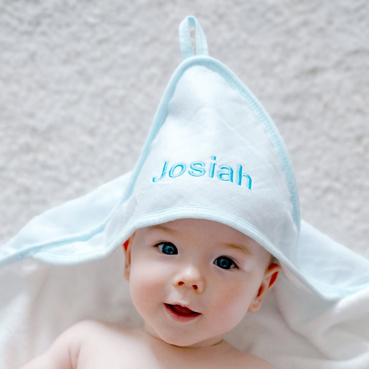 Baby wearing Blue Bamboo Hooded Towel Personalised with "Josiah" in Blue Thread