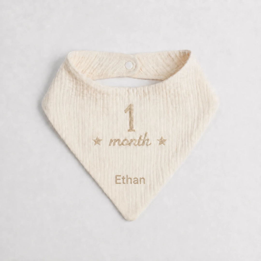 Baby bib with embroidered text on a light gray background