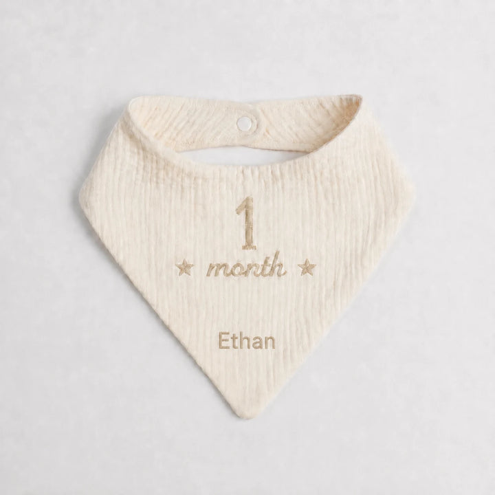 Baby bib with embroidered text on a light gray background