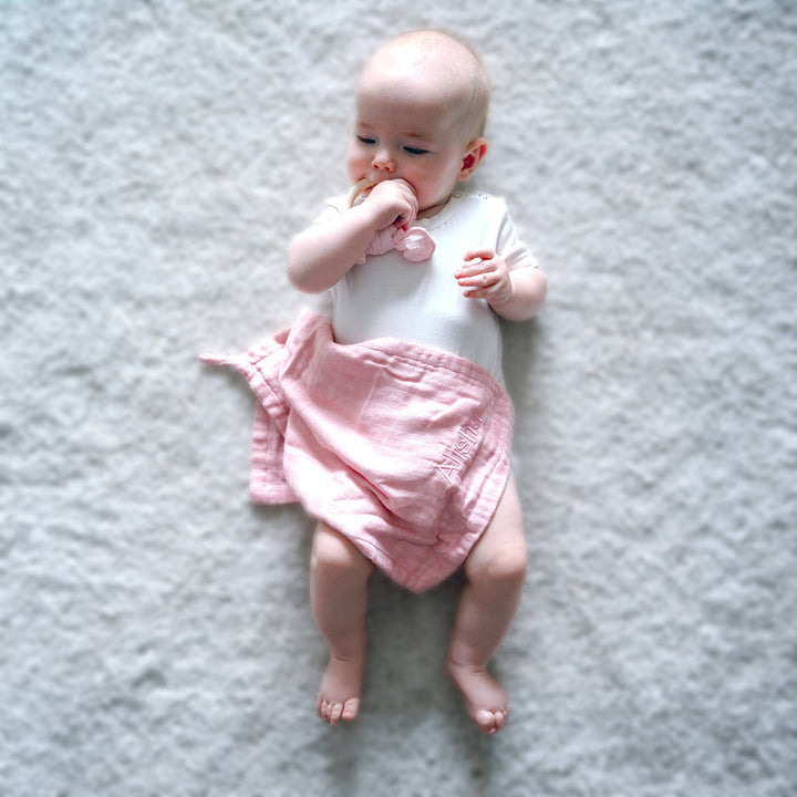 Baby using Pink muslin washcloth
 