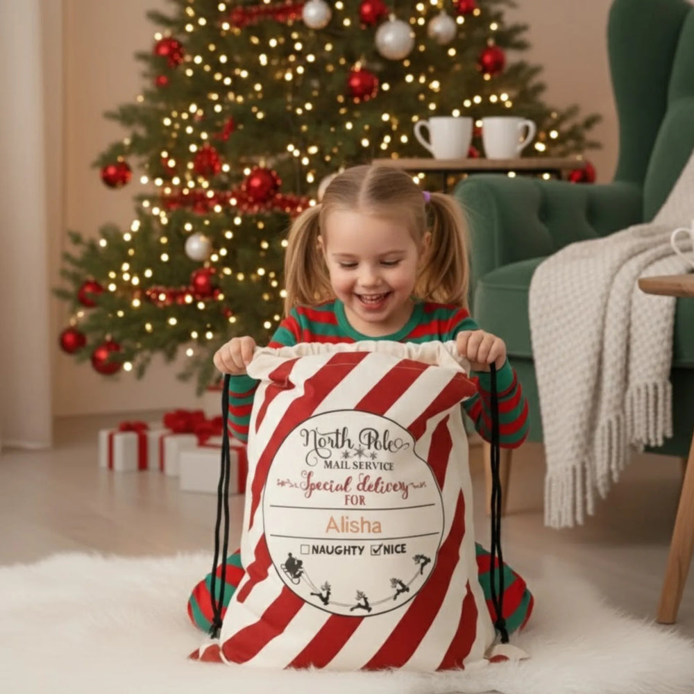 Little Girl opening her personalized Christmas sack in front of a decorated tree