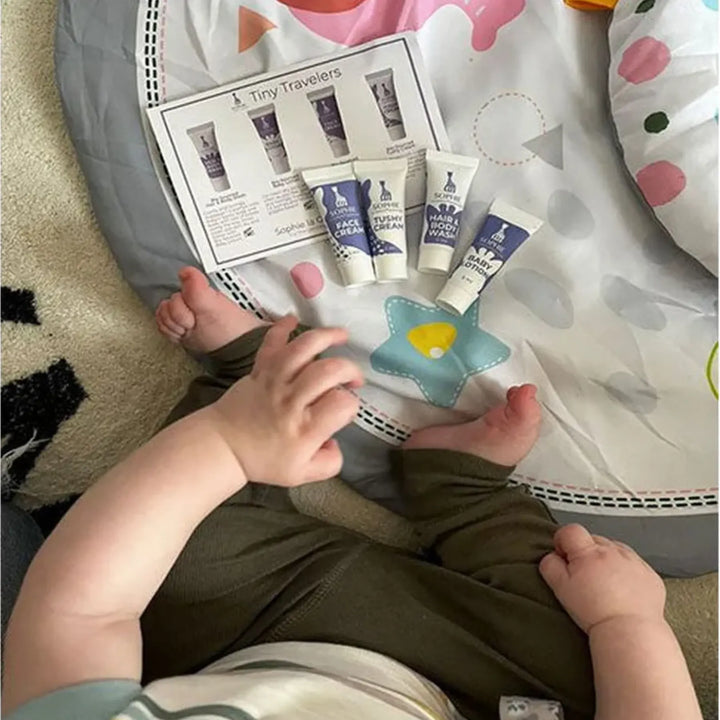 Baby holding a product catalog with baby care items on a soft surface