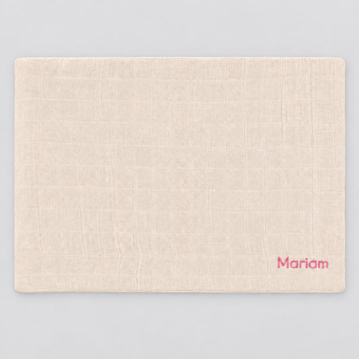 Blossom Trixie muslin blanket laid flat on a light grey studio background, personalised with the name “Mariam” embroidered in pink at the bottom right corner.