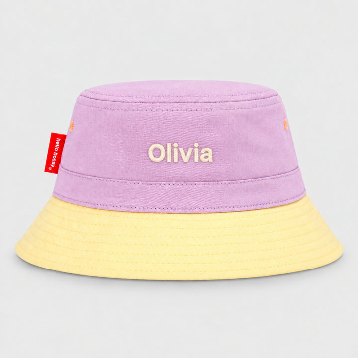 Back view of a lilac and cream Hello Hossy bucket hat personalised with “Olivia” in cream block embroidery and red side tag.
