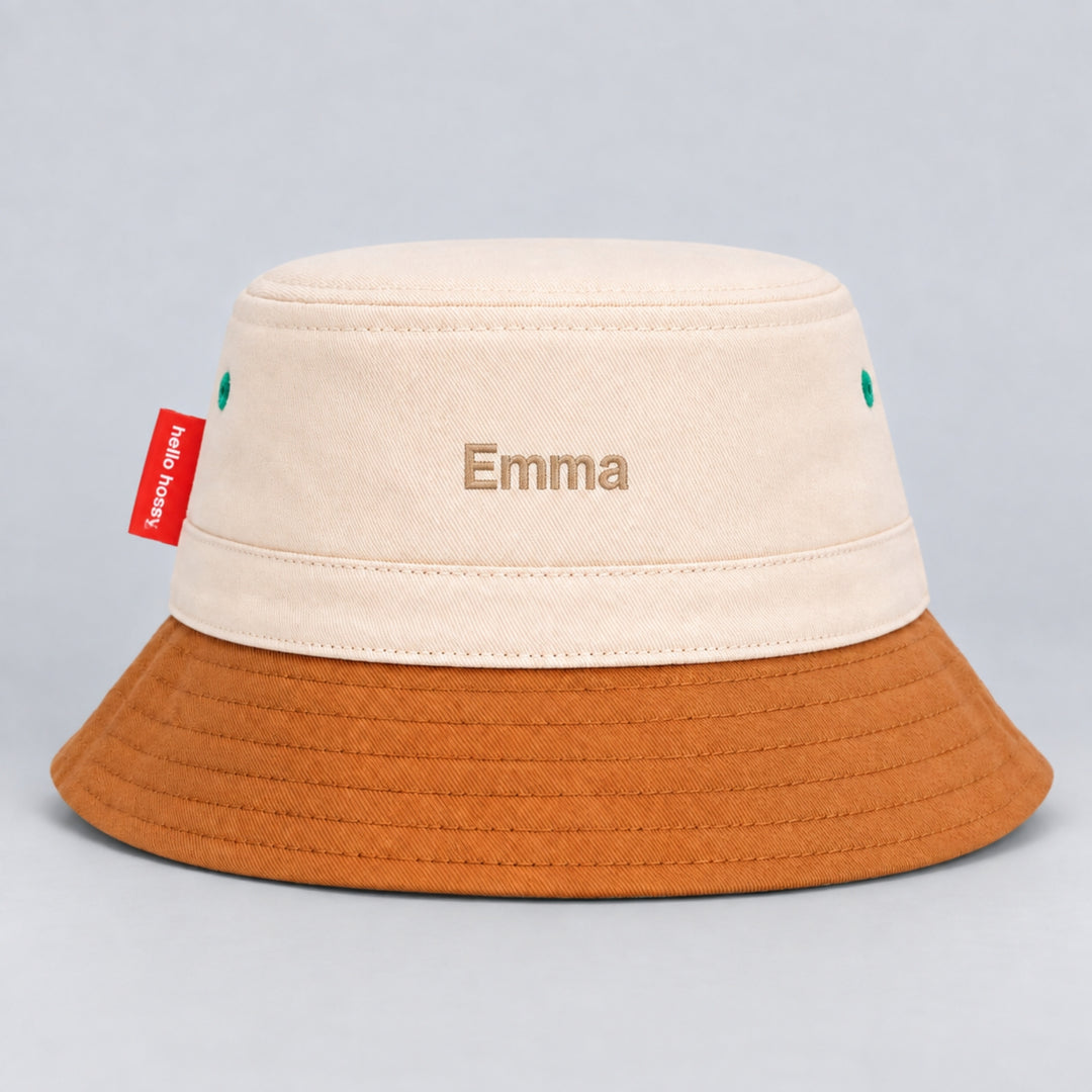 Back view of a cream and brown Hello Hossy bucket hat personalised with “Emma” in beige block embroidery and red side tag.