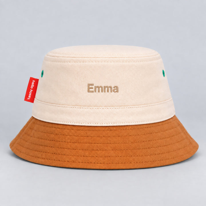 Back view of a cream and brown Hello Hossy bucket hat personalised with “Emma” in beige block embroidery and red side tag.
