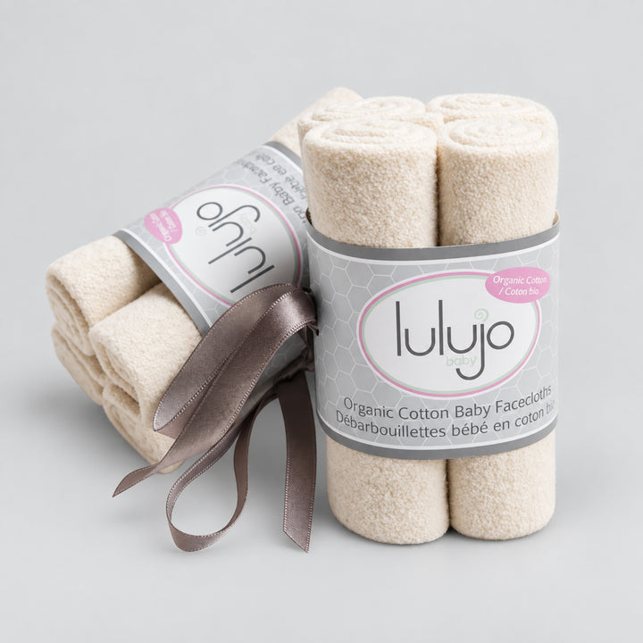 Lulujo organic cotton baby face cloths in cream, rolled and bundled in grey branded packaging with a ribbon.