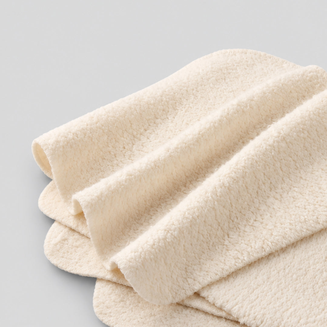 Close-up of soft cream organic cotton baby face cloths showing the plush terry texture and stitched edges.