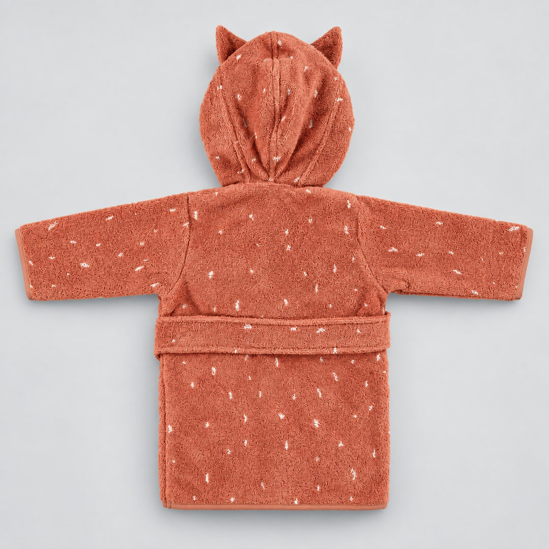 Back view of a terracotta pink children’s cat bathrobe laid flat on a seamless light grey studio background. The robe features a hood with pointed cat ears, white speckled detailing, long sleeves, and a matching waist belt.