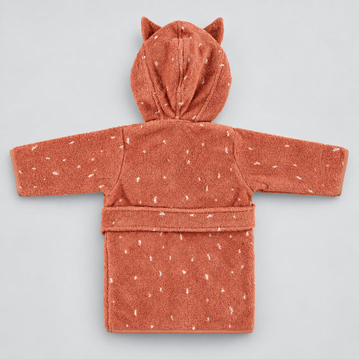 Back view of a terracotta pink children’s cat bathrobe laid flat on a seamless light grey studio background. The robe features a hood with pointed cat ears, white speckled detailing, long sleeves, and a matching waist belt.