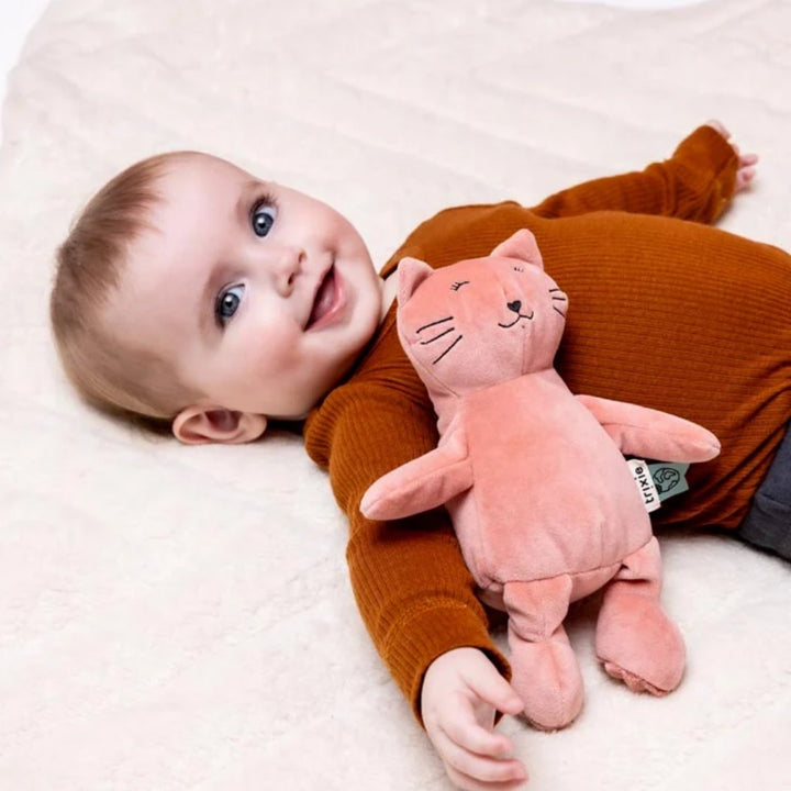 Baby lying with Trixie Cat soft toy in coral pink, cuddly plush companion UAE