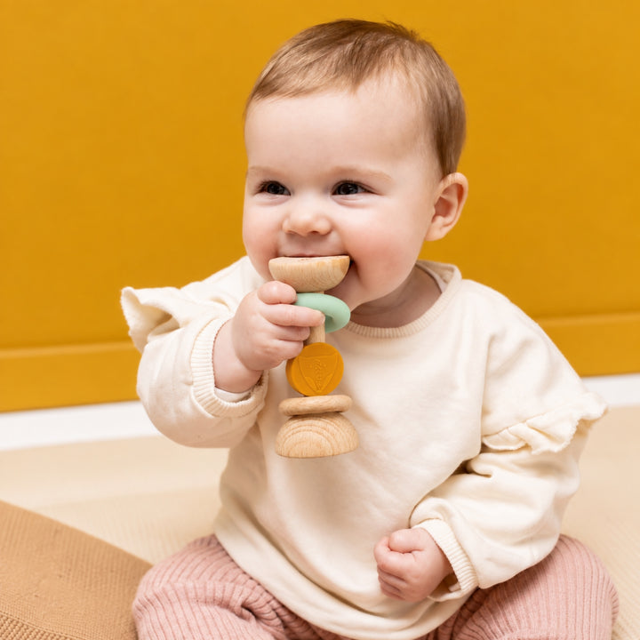 Baby holding Trixie Fox wooden and silicone rattle teether, sensory baby toy UAE