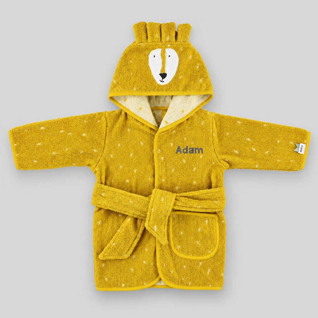Mustard yellow children’s lion bathrobe laid flat on a light grey studio background, featuring a lion face hood, white speckled pattern, matching belt and pocket, personalised with the name “Adam” in grey embroidery on the chest.