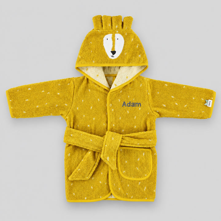 Mustard yellow children’s lion bathrobe laid flat on a light grey studio background, featuring a lion face hood, white speckled pattern, matching belt and pocket, personalised with the name “Adam” in grey embroidery on the chest.