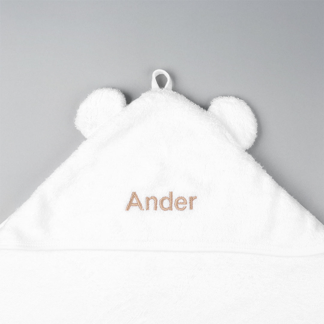 Closeup of white baby hooded towel with "Ander" in beige thread
