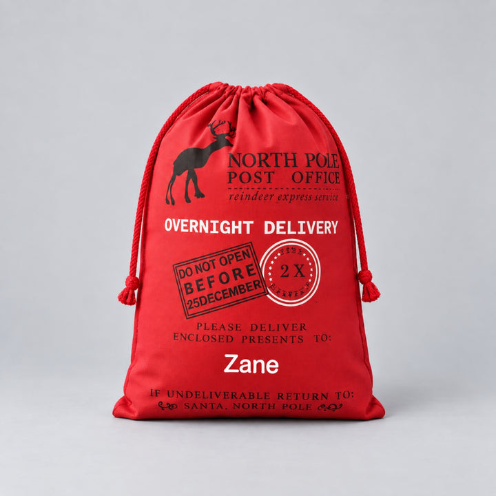 Personalised red Christmas drawstring sack with North Pole Post Office and reindeer delivery design, finished with the name “Zane”.